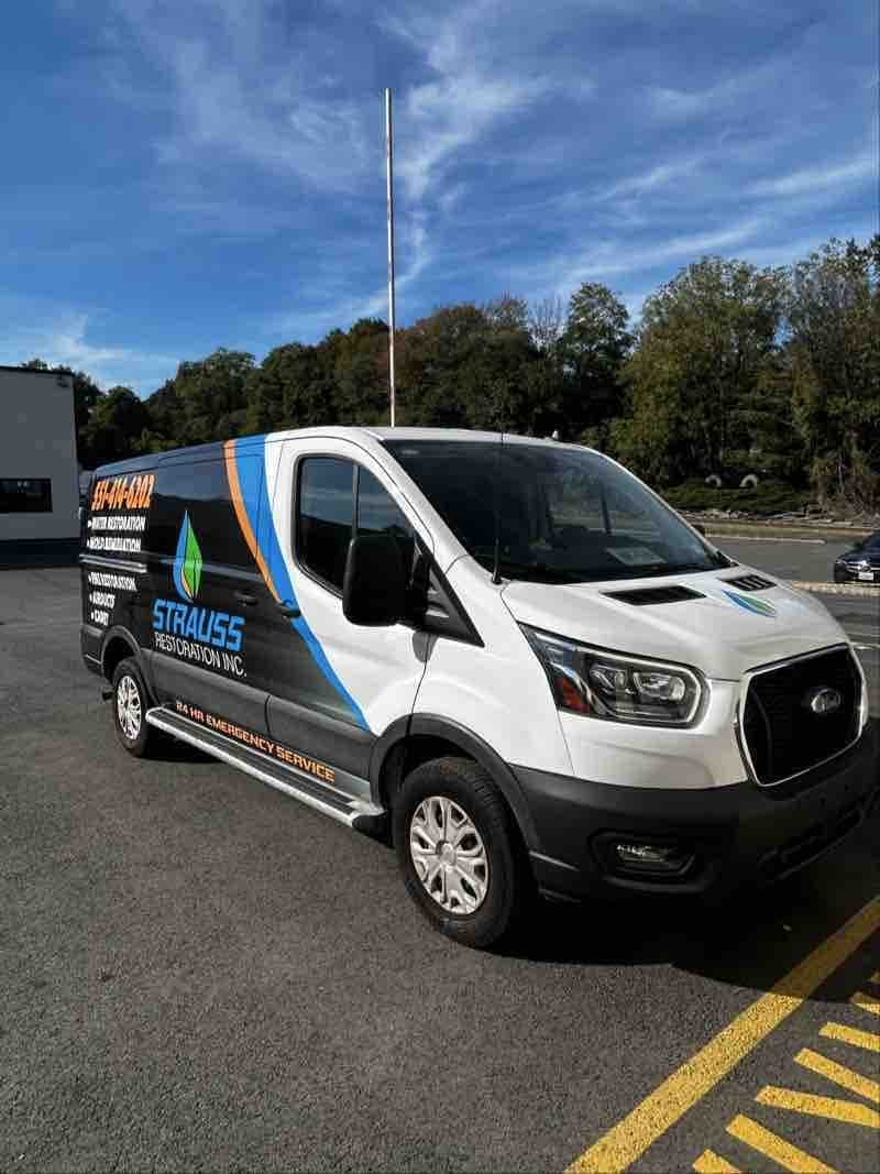 Front three-quarter view of the Strauss Restoration wrapped work van parked in a lot